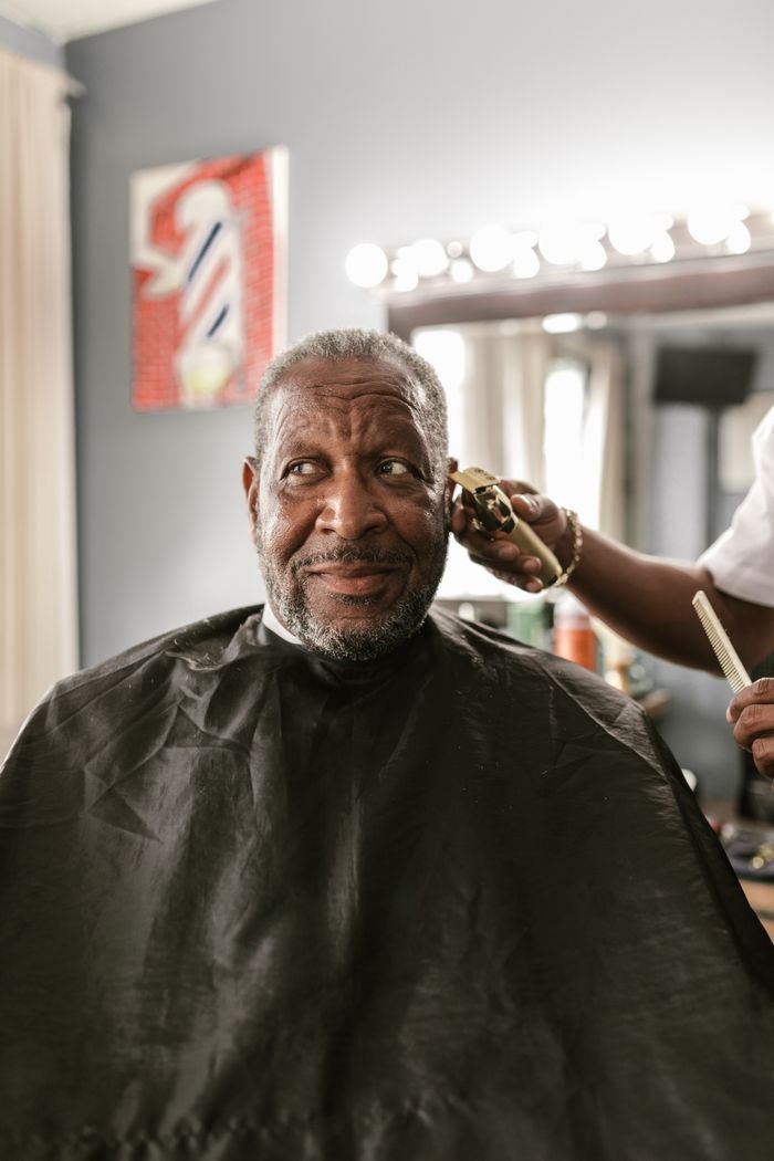 why-choose-us-02 African American man receiving a trim in a barbershop with stylist in action.