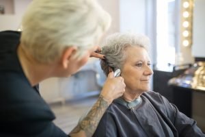 An elderly woman receiving a haircut from a skilled stylist in a contemporary salon.