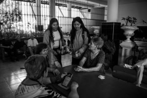 Black and white photo of a community gathering with people of different ages interacting indoors.